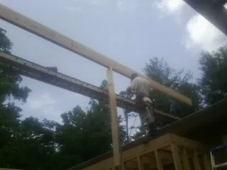 Carpenter setting a ridge beam over a new addition frame — Ice Dam Removal by Roofing Brothers in Clitherall