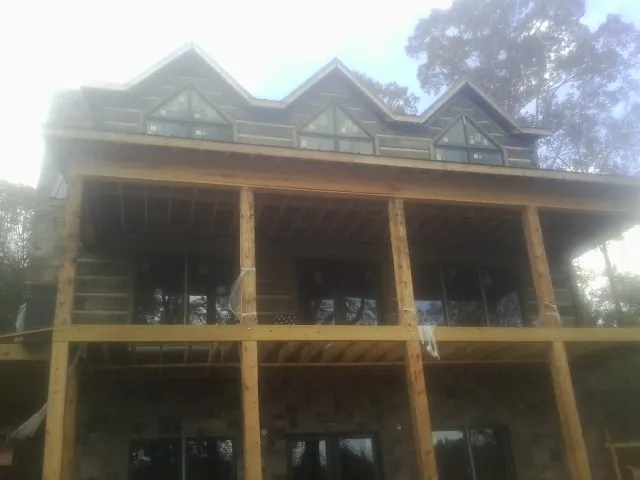 Dormers and porch framing on a large log home under construction — Roof Coating work by our crew in Clitherall