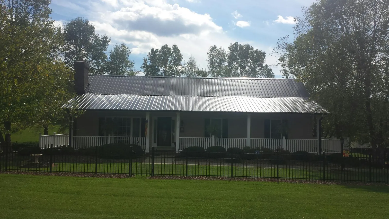 Gray metal roof on a brick ranch with a full width front porch — Gutter Guard Installation work by our crew in Clitherall